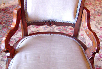 One of twelve matching chairs from Harrison's dining room. Walnut with seats and backs upholstered. Two carved spindle supports go across between the front legs. Two plain supports cross between the legs at the sides and back. Small side decorative supports (not Arms) go from the lower part of the back to the seat. The back, sides, and apron under the seat have an incised carved design. They are American Eastlake style dating from the 1870s.