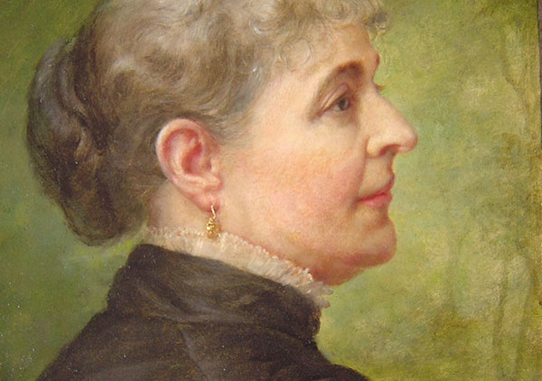 Oil on canvas by Lilly M. Spencer (Lilly Martin Spencer) of Caroline Scott Harrison in profile view. Spencer signature is in lower left (not visible when portrait is in frame). Many engravings and prints were made from this image of Caroline Harrison. She is wearing a dark dress with white lace trim at the high neck, gold earrings, and hair is pulled back in a bun. Background is green in varying dark to medium shades. Pat. date of 1885 on metal corner brackets of wooden stretcher.