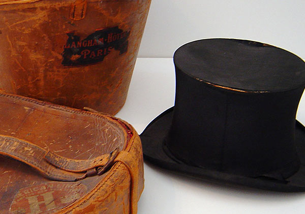 Opened view of the top hat case. Shows a red velvet interior shaped to accommodate the hat.