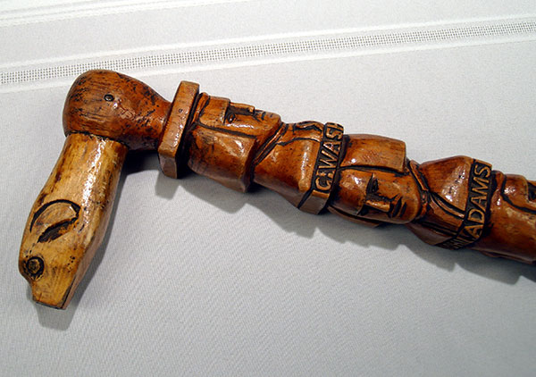 Centennial walking stick, contains hand carved images (head and shoulders in relief) of all the Presidents from Washington to Benjamin Harrison with name below each. They are on both sides of the cane coming down to Harrison. Wood is white pine and stained. The carved handle is an animal head design. Three of the president's names are misspelled: Madison, Hayes, and Arthur.