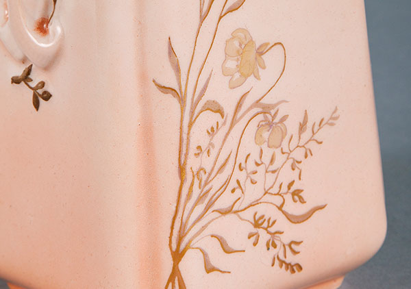 close up photo of the chocolate pot. shows intricate gold painting of delicate flowers, coming from the corner and traveling halfway up the side of the pot.