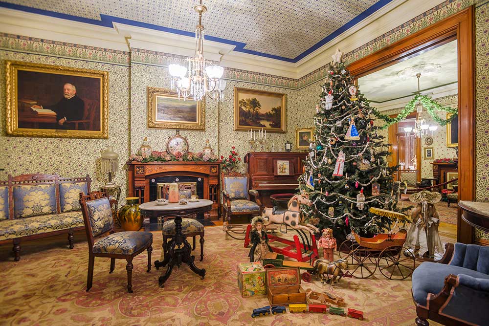 Photograph of harrison's front parlor, fully decorated with a large festive tree, ready for the holidays.
