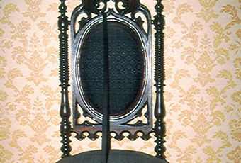 Gothic or Elizabethan rival chair circa 1850 that belonged to the Harrison family. It has been reupholstered in horse hair fabric with a diamond pattern. Back of chair is an oval shape with carved top ornament and side spooled spindles. Legs are also spooled spindles.