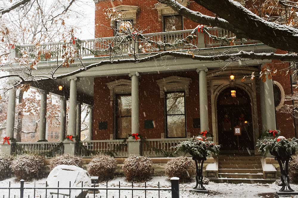 Photo of the Benjamin Harrison Presidential Site's front porch, dusted with snowfall and adorned with small holiday decorations.